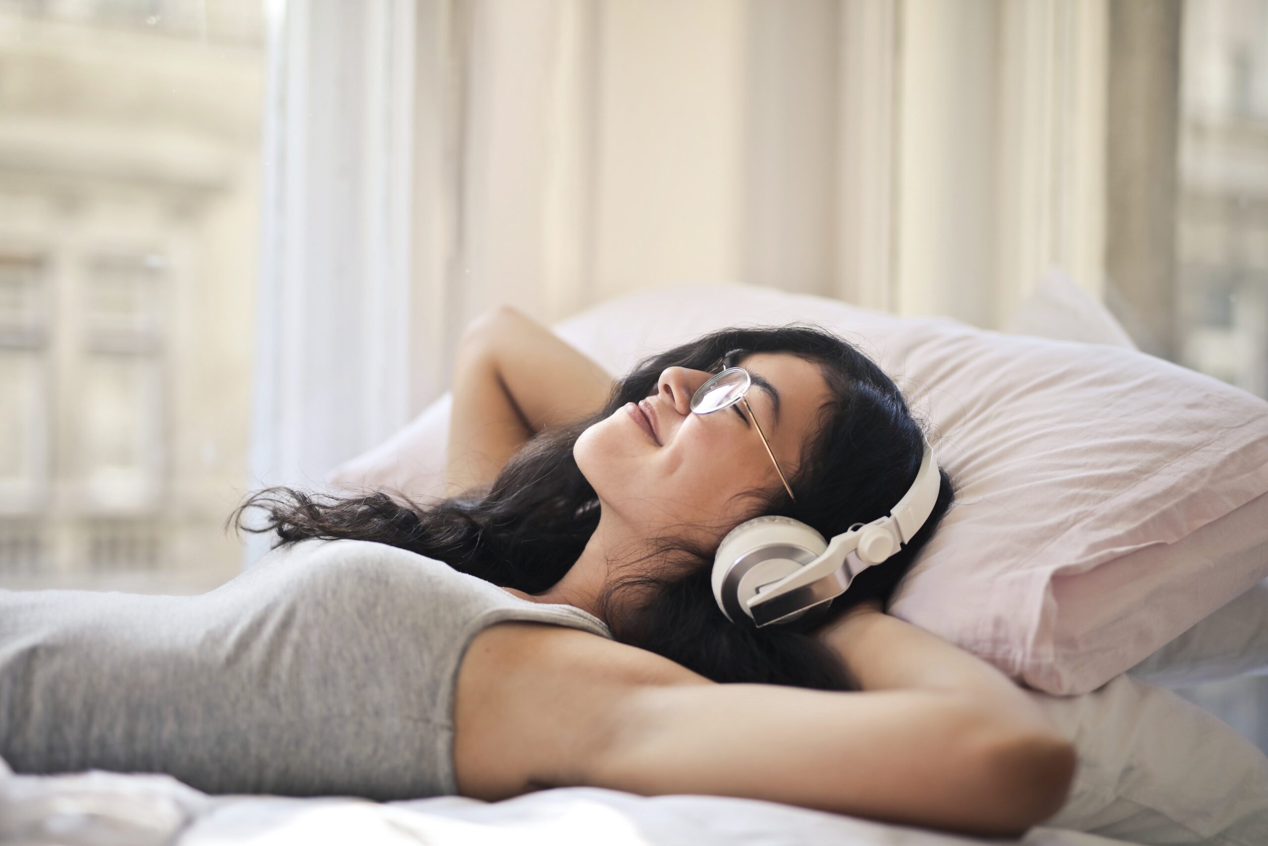 kobieta słucha muzyki ze słuchawkami leżąc na łóżku